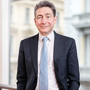 Portrait, dunkler Anzug, Hintergrund Universität